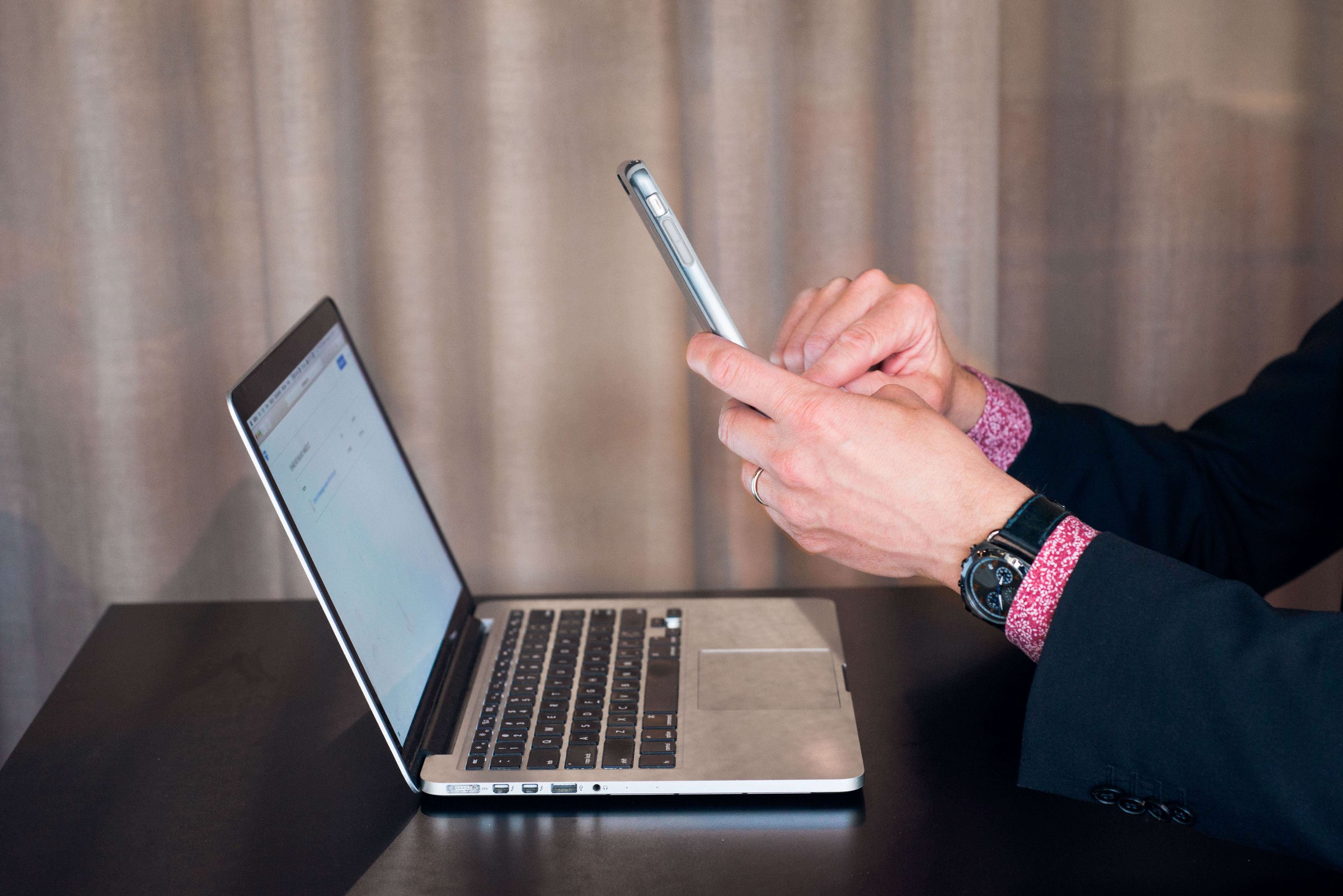 Close-up of Niklas’s hands with a phone and a laptop