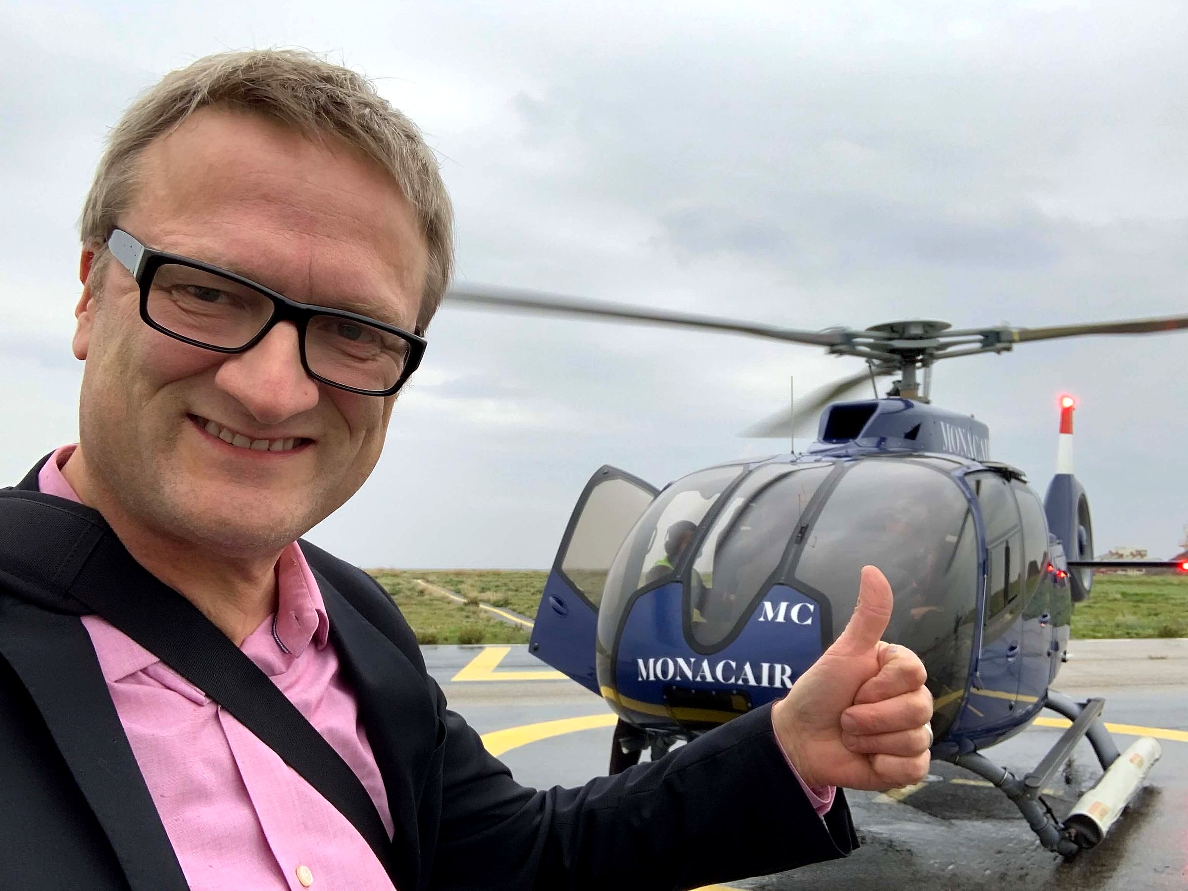 Niklas giving a thumbs-up beside a Monacair helicopter