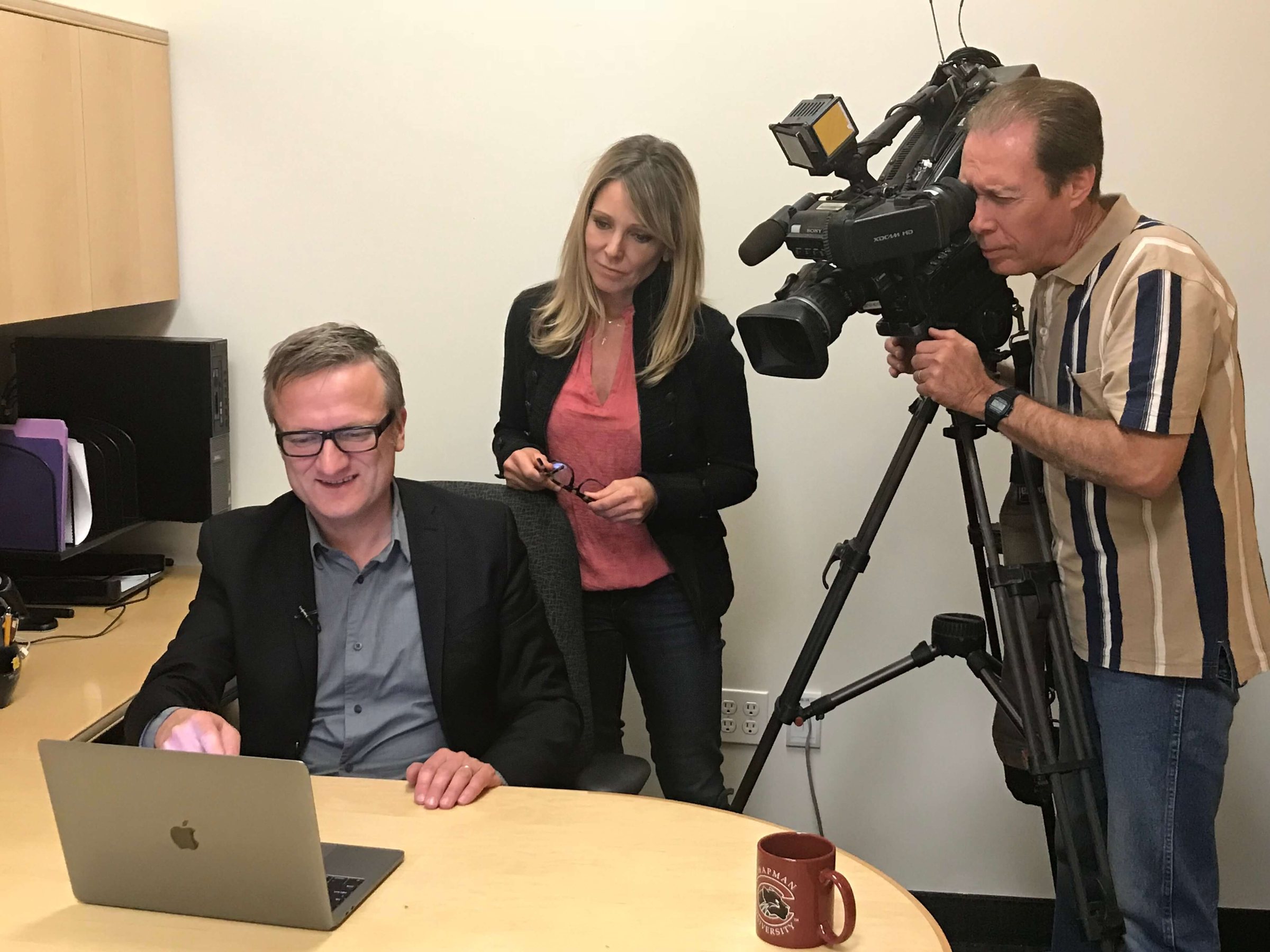 CBS LA reporter Stacey Butler and a camera operator filming Niklas at his desk