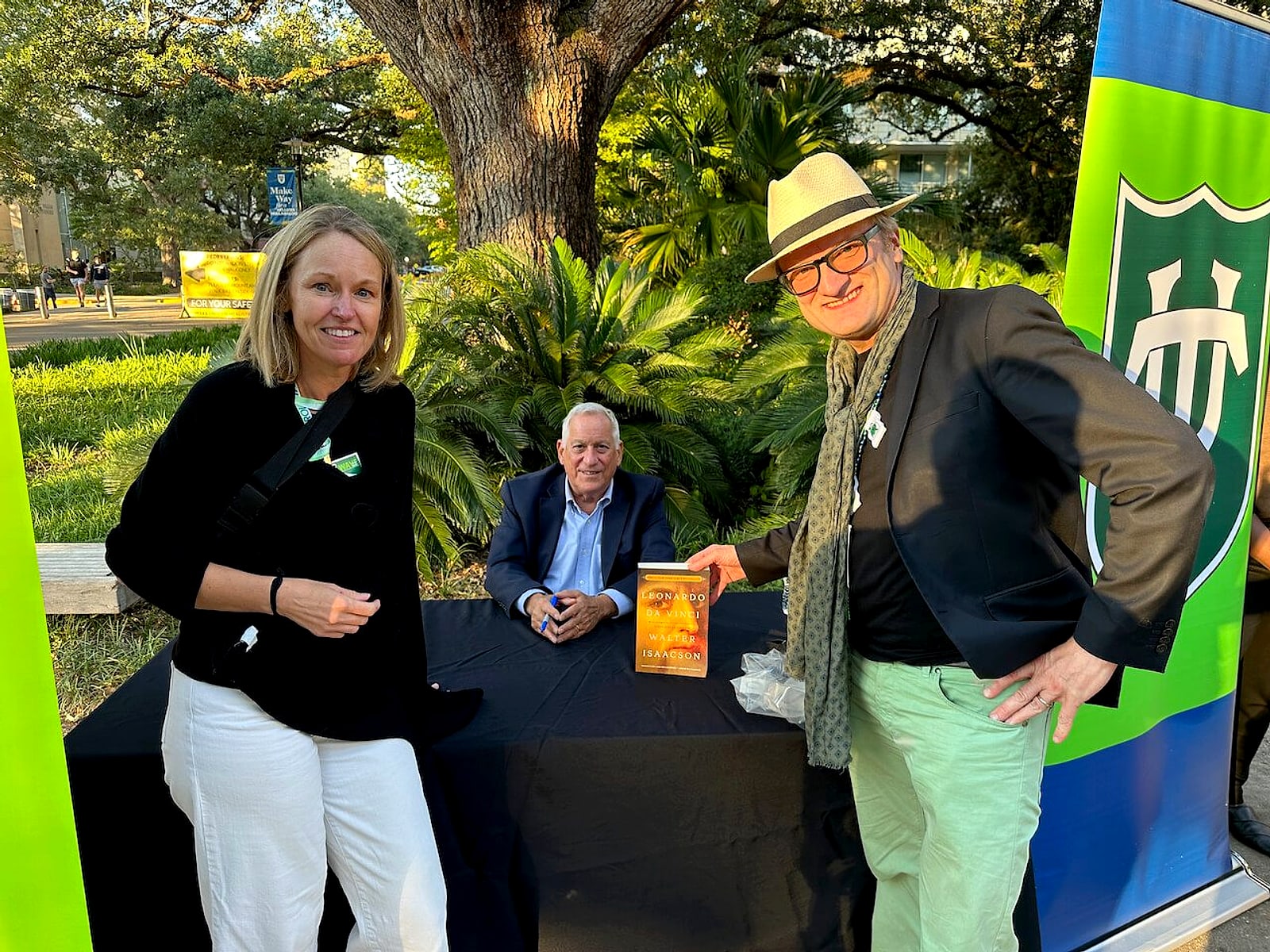 Walter Isaacson signing books at Tulane University, Niklas in a hat beside the table